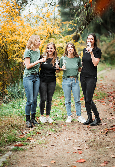 Vier Pfalz Herz Mitglieder mit Weinglas in der Hand im Rebenmeer